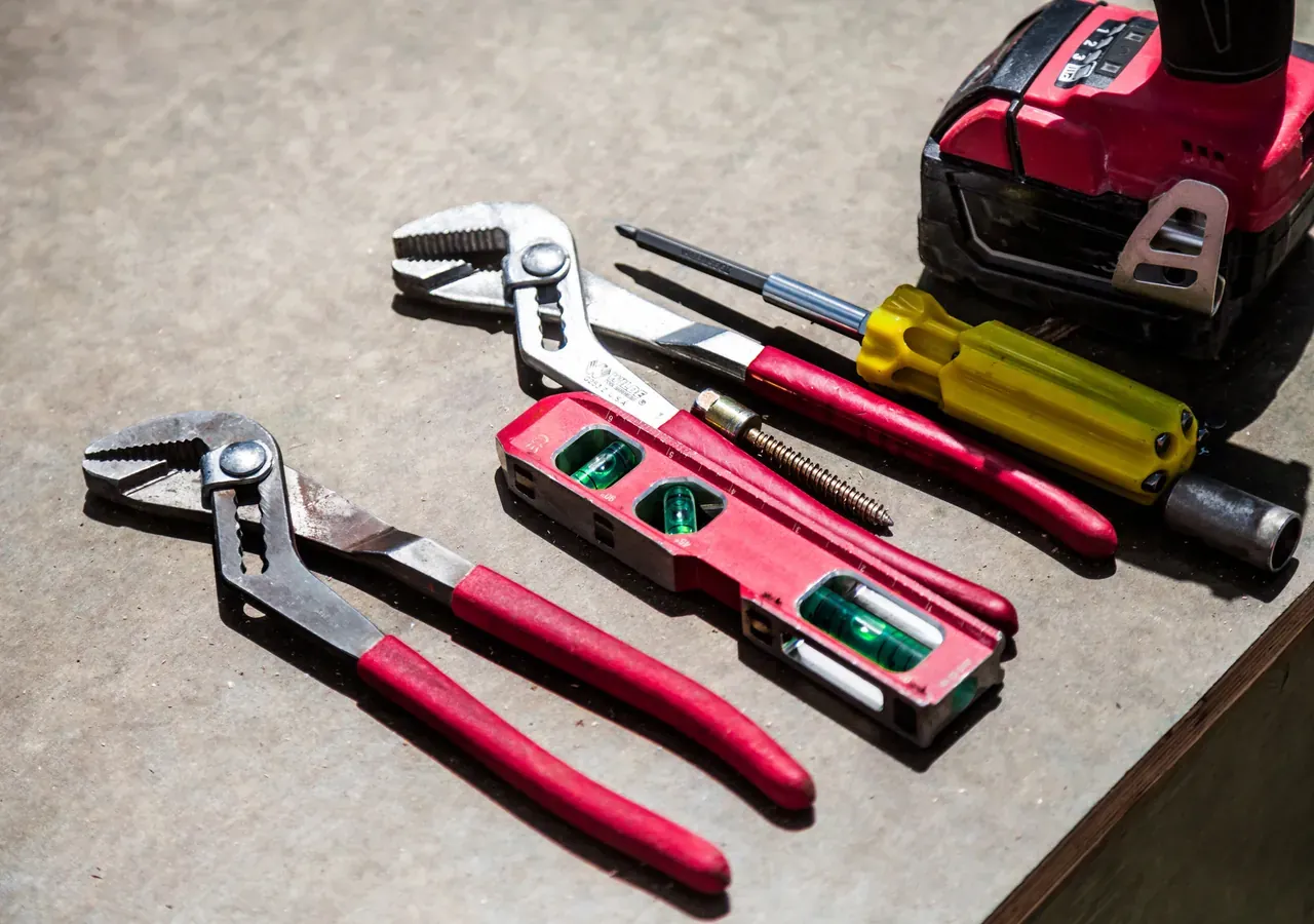 A heating engineer's pipe wrench, spirit level and tools on a workbench