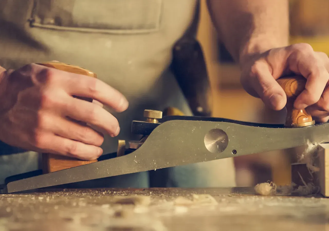 A joiner planing a piece of wood in a workshop